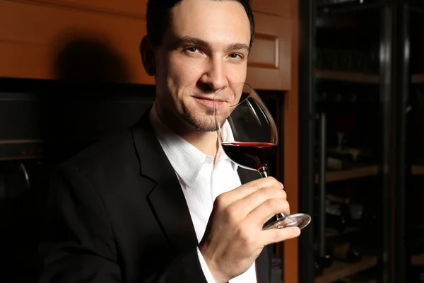 Άνθρωπος με ποτήρι κόκκινο κρασί στο σύγχρονο κελάρι — Φωτογραφία Αρχείου