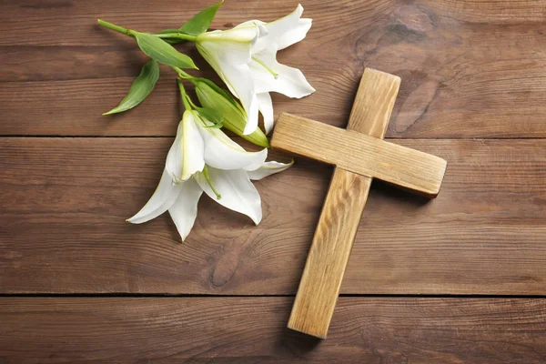 木制十字和白色百合花放在桌上 — 图库照片