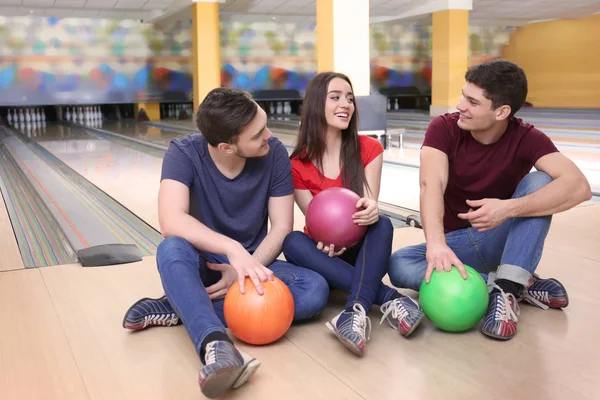 Amigos sentados en el suelo en el club de bolos —  Fotos de Stock