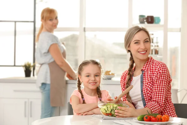 Wanita muda dengan putri dan ibu di dapur — Stok Foto