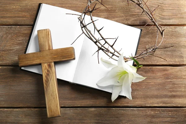 Crown of thorns, Holy Bible, wooden cross and white lily on table