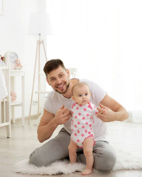 Father sitting with cute baby daughter on floor at home — Stock Photo, Image