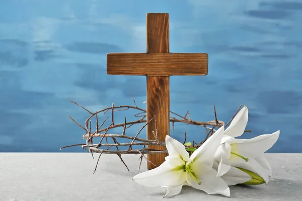 Corona de espinas, cruz de madera y lirio blanco sobre la mesa —  Fotos de Stock
