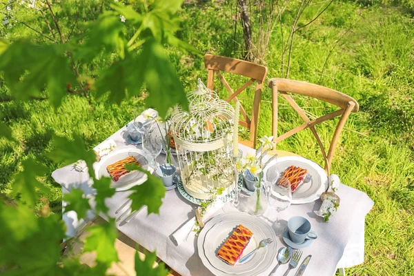 Tischdecke und Käfig mit Blumen — Stockfoto