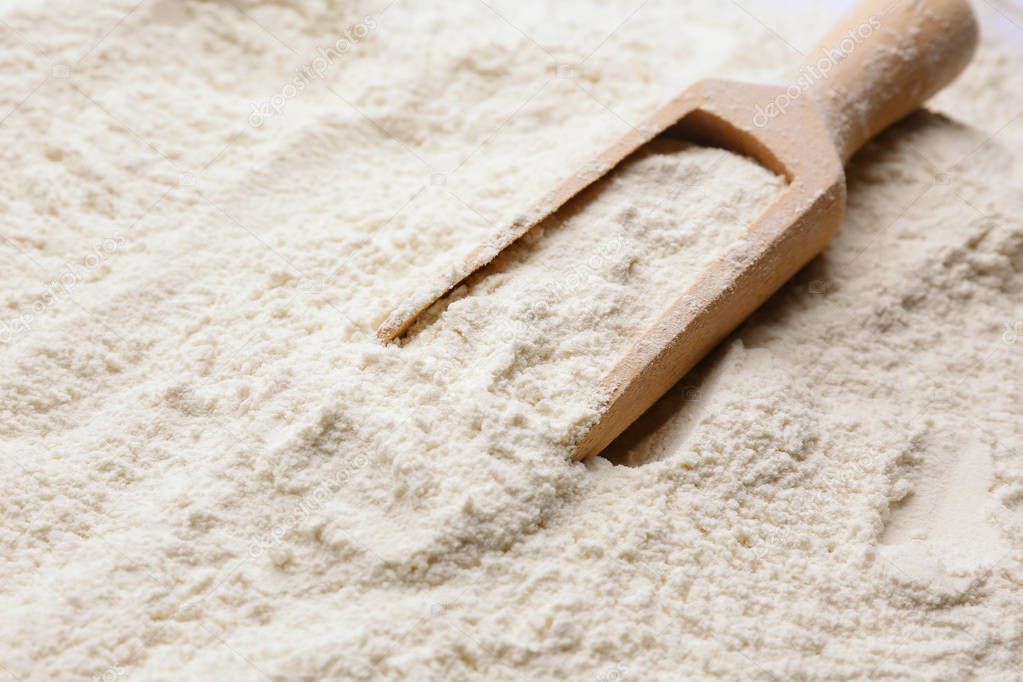 Wooden scoop on wheat flour