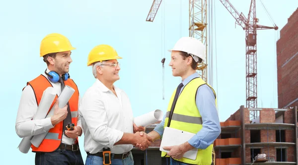 Ingenieurteam mit Projektzeichnungen und Baustelle im Hintergrund — Stockfoto