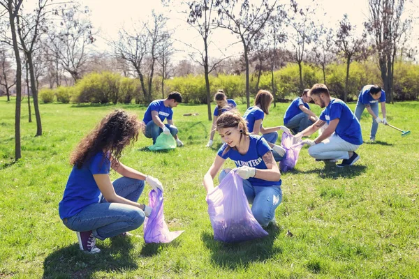 Groupe de jeunes bénévoles ramassant des ordures dans le parc — Photo