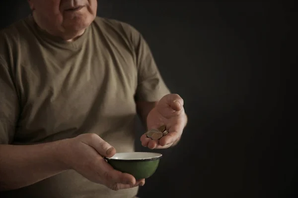 在黑暗背景下有碗和硬币的老人 贫穷概念 — 图库照片