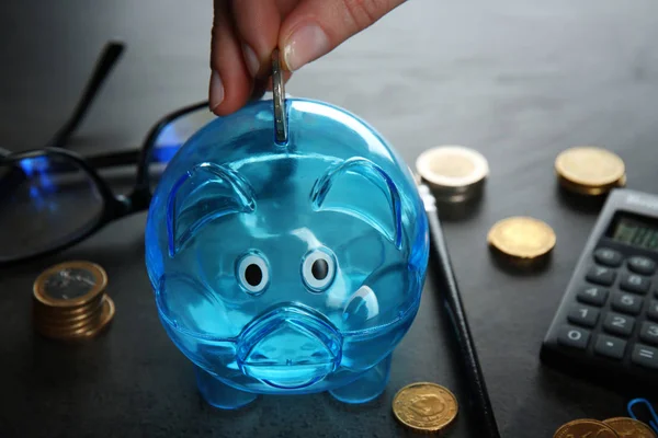 Hand steckt Münze in Sparschwein — Stockfoto