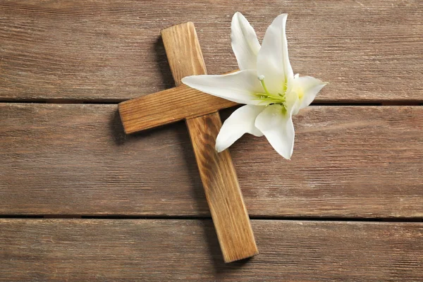 Wooden cross and white lily on table — Stock Photo, Image