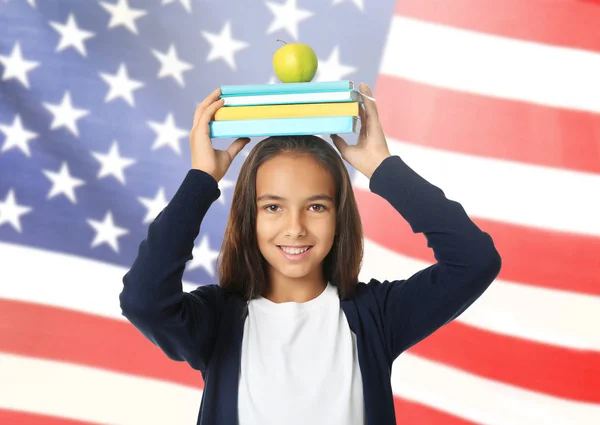 Petite fille avec pomme et livres sur fond drapeau des États-Unis — Photo