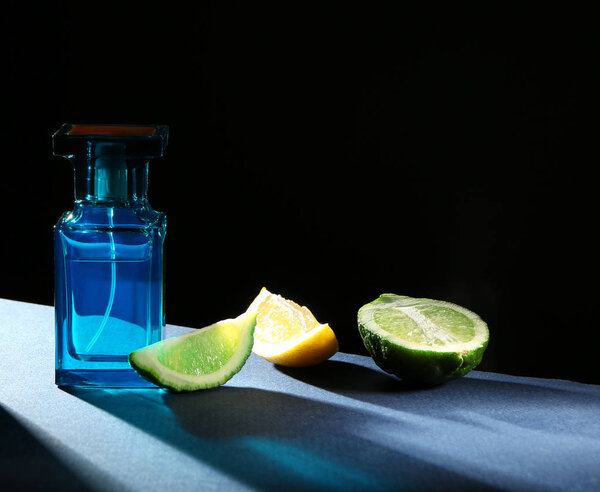Бутылка современных мужских духов и цитрусовых ломтиков на темном фоне
