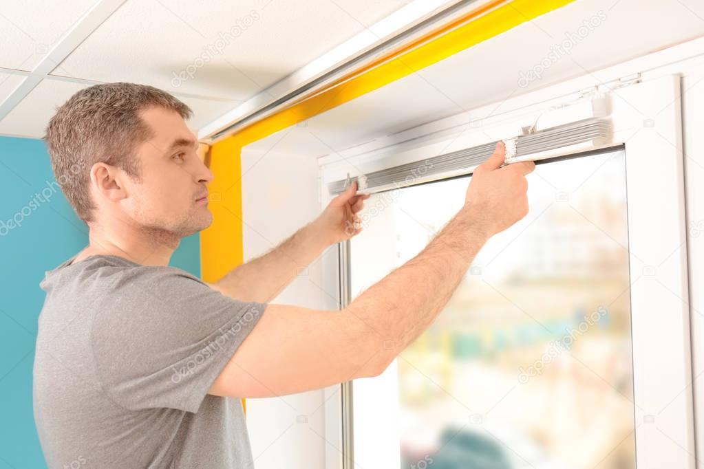 Young man installing window shades 