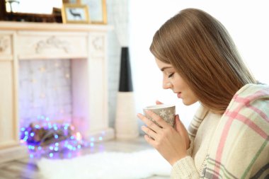 Evde bir fincan kahveyle güzel genç bir kadın.