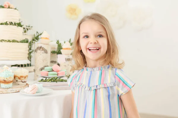 Симпатичная девушка за столом с сладостями, подаваемыми на вечеринку — стоковое фото