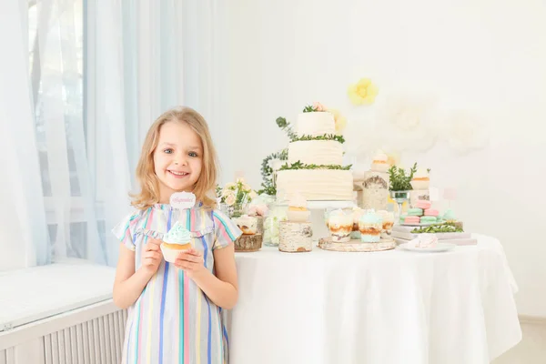 Симпатичная девушка за столом с сладостями, подаваемыми на вечеринку — стоковое фото