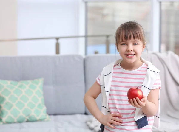 Gelukkig schoolmeisje staande met apple thuis — Stockfoto