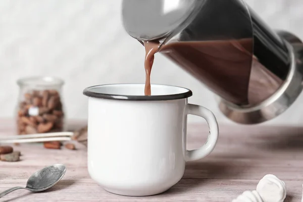 Pouring hot cocoa drink into mug — Stock Photo, Image