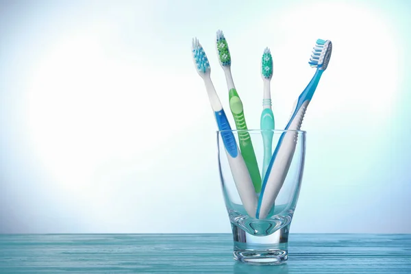 Tandborstar i glas på färgbakgrund — Stockfoto
