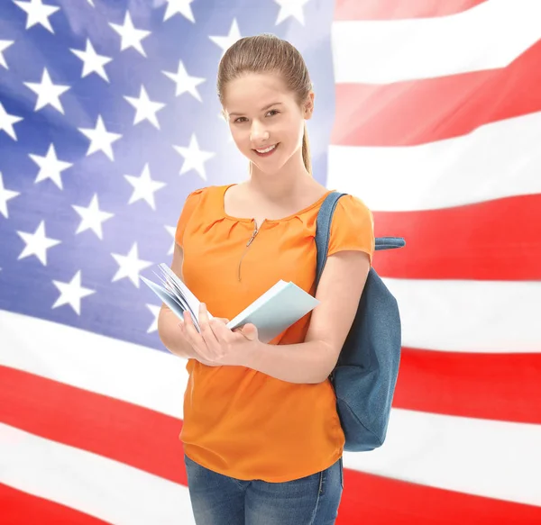 Teenage girl with backpack and book on USA flag background — Stock Photo, Image