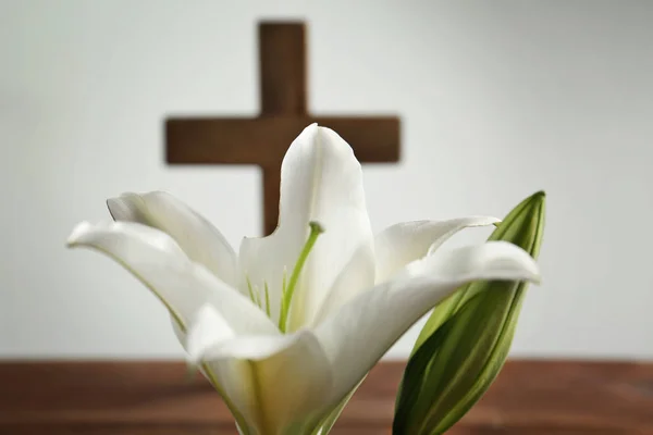 Weiße Lilie und verschwommenes Holzkreuz auf Hintergrund — Stockfoto