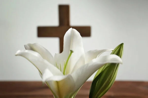 Lirio blanco y cruz de madera borrosa sobre fondo — Foto de Stock