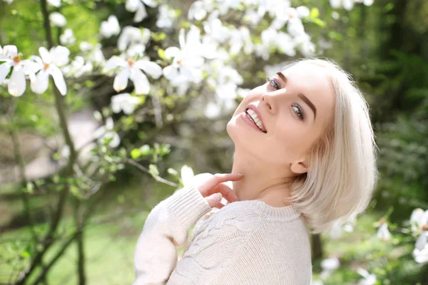 Ung blond kvinne nær blomstrende tre – stockfoto