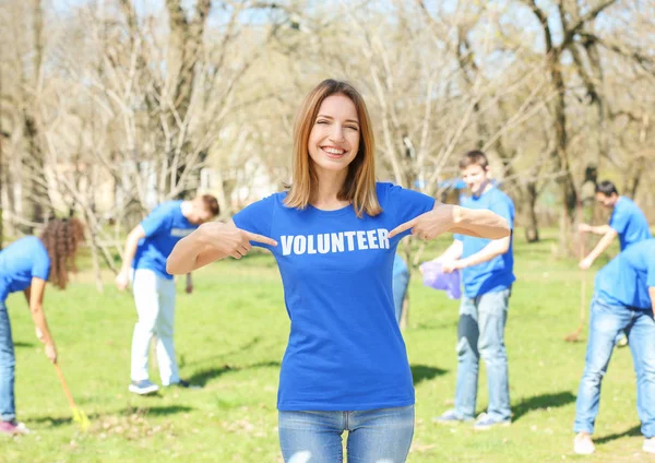 Beautiful young volunteer with team outdoors — Stock Photo, Image