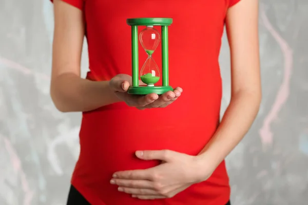 Pregnant woman holding hourglass — Stock Photo, Image