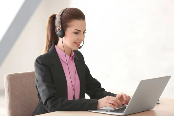 Jonge vrouw met hoofdtelefoon en laptop werken in office — Stockfoto