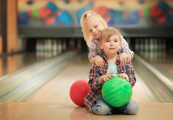 Słodkie dzieci z kulkami, siedząc na podłodze w bowling club — Zdjęcie stockowe