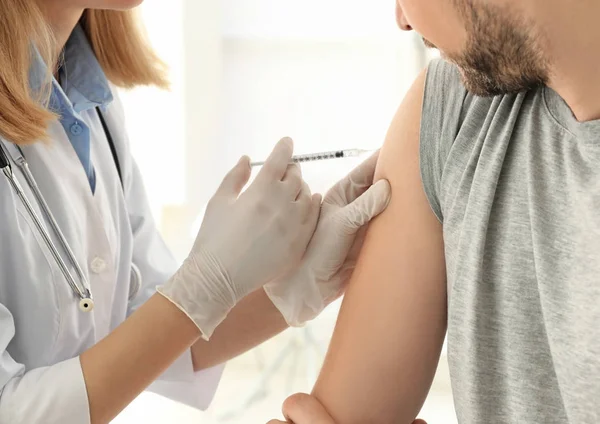 Concept van de vaccinatie. Vrouwelijke arts vaccinerend jongeman — Stockfoto