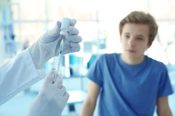 Mãos de médico preparando-se para a vacinação e paciente desfocado em segundo plano — Fotografia de Stock