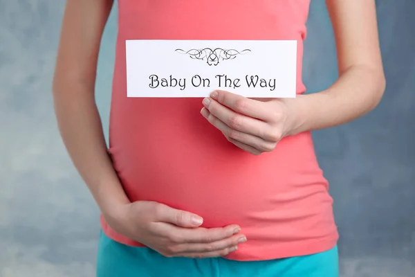 Donna incinta che tiene la carta con le parole BABY ON THE WAY — Foto Stock