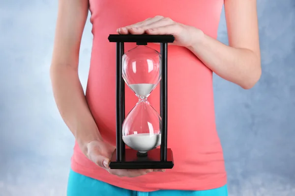 Беременная женщина держит песочные часы — стоковое фото