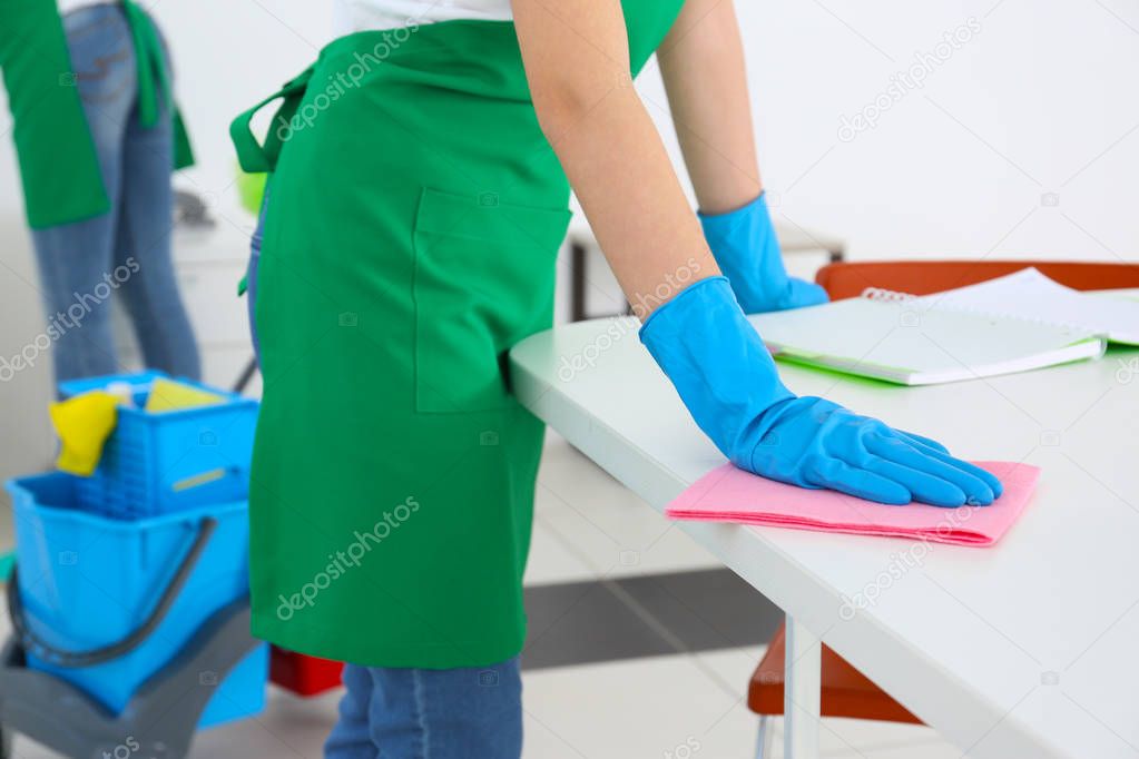 Young woman cleaning office table, closeup