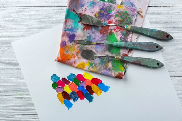 Paper with oil paint strokes and palette knives on table — Stock Photo, Image