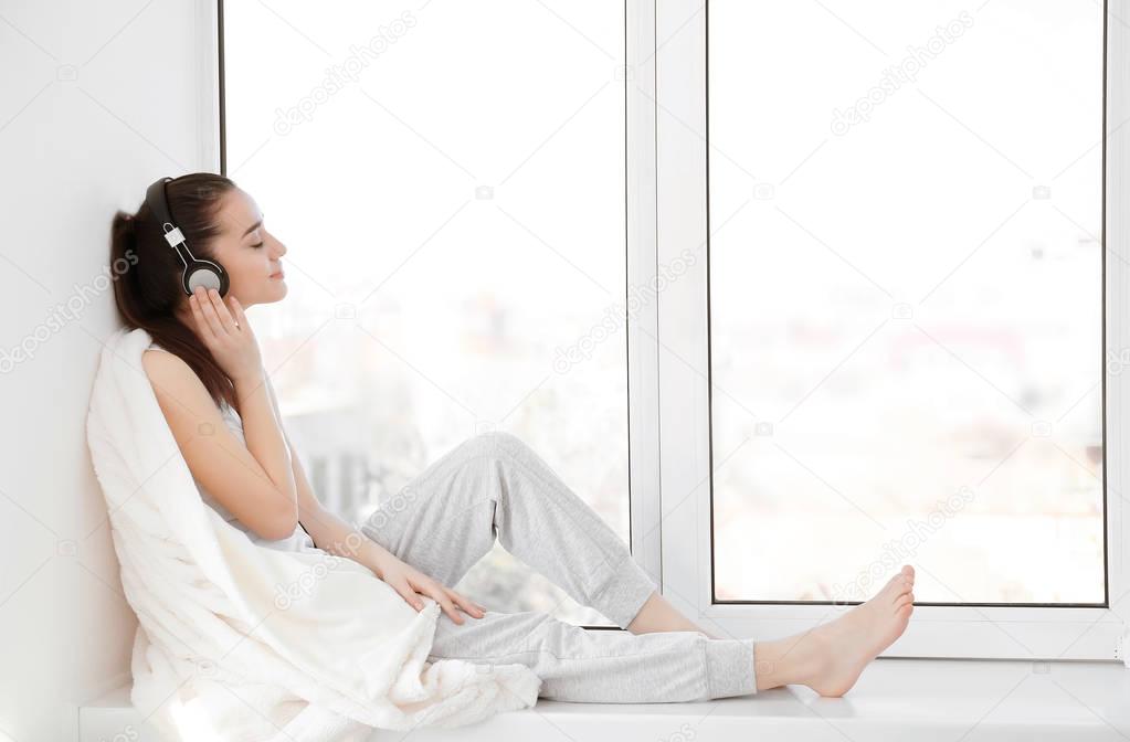 woman sitting on windowsill and listening to music