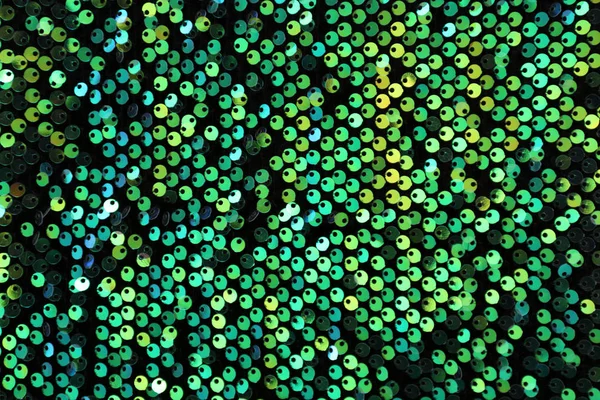 Green paillettes on dark fabric — Stock Photo, Image