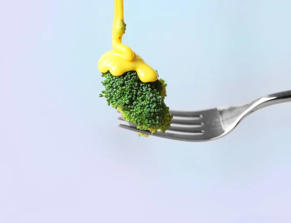 broccoli and pouring cheese sauce