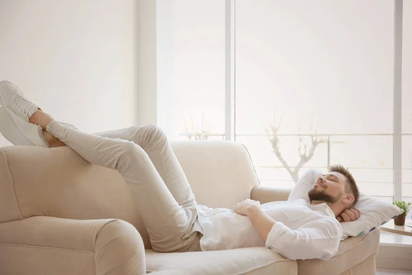 Junger Mann ruht sich auf Sofa aus — Stockfoto