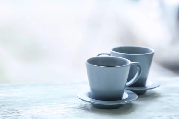 Cups with hot tea on wooden table against blurred background — Stock Photo, Image