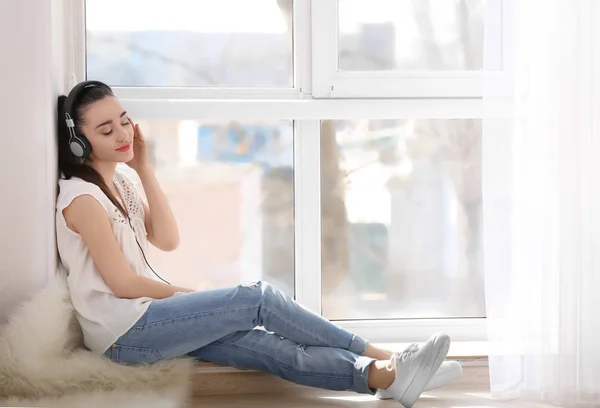 Mujer sentada en el alféizar de la ventana y escuchando música —  Fotos de Stock