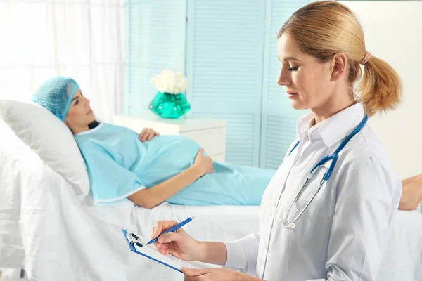 Doctor filling medical record of pregnant woman — Stock Photo, Image