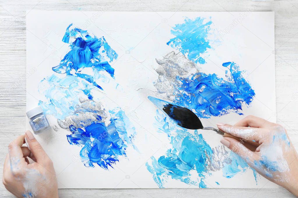 Female hands painting abstract picture with oil paint strokes, closeup