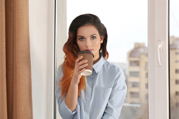 Belle jeune femme buvant du café près de la fenêtre à la maison — Photo
