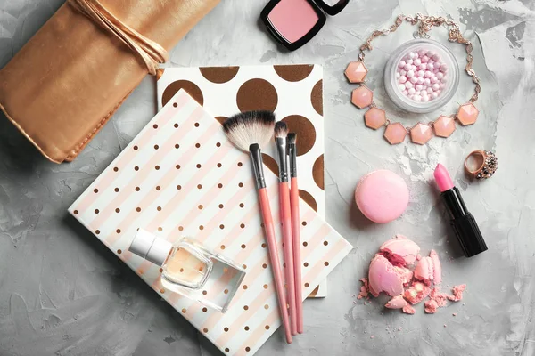Samenstelling van cosmetica, parfum, notebooks en gebak op grijze achtergrond — Stockfoto