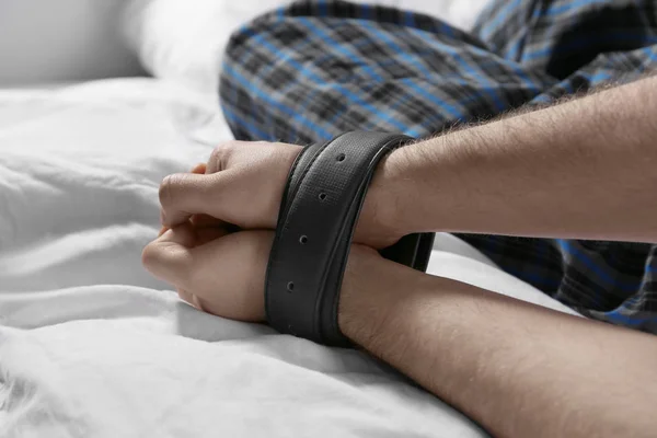 Male hands tied up with belts in bed — Stock Photo, Image