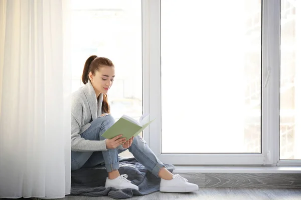 Vrouw zittend op een vensterbank en lezen — Stockfoto