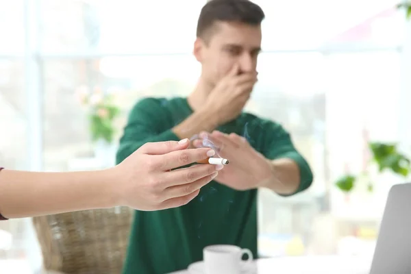 Passiv rökning koncept. Ung man som täcker ansiktet från cigarettrök — Stockfoto